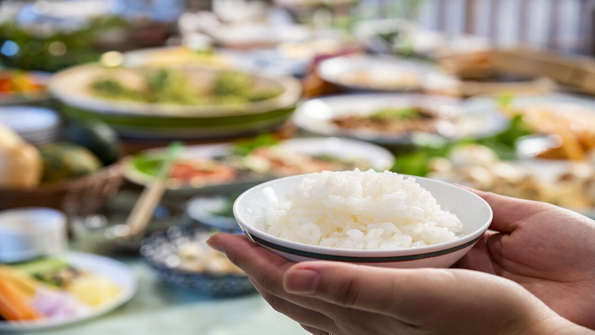 Una mano sosteniendo un tazón de arroz blanco.