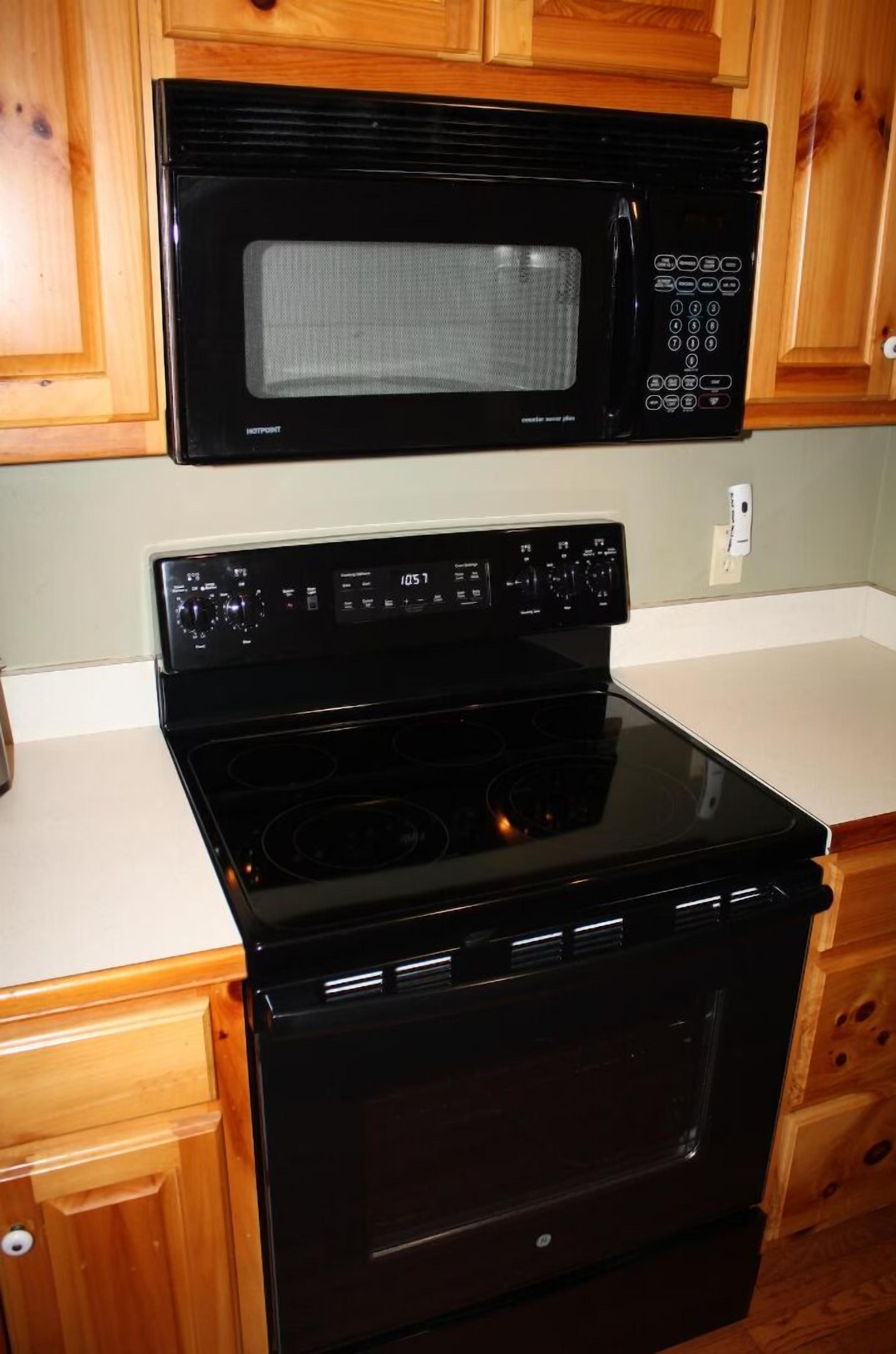 A kitchen with a black microwave and stove.