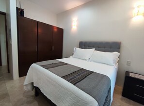 A bedroom with a bed, a wardrobe, and a nightstand. - Charm condo 5 min from the beach! 2-bedroom condo with balconies. (Crucecita)