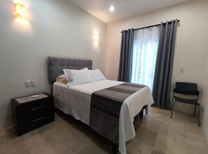A neatly arranged bedroom with a bed, bedside table, and a chair.