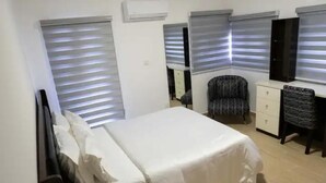 A bedroom with a bed, a dresser, a chair, and a TV. - Canalily Apt

 (Lekki)