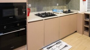A kitchen with a microwave, stove, and oven. There is a red kettle and a sink with a faucet. A fire extinguisher is mounted on the wall. - Canalily Apt

 (Lekki)