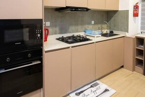 Kitchen features a gas stove, black range hood, and stainless steel sink.