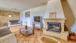 Ein Wohnzimmer mit Steinwand, Kamin, einer Couch, einem Couchtisch und einem Fernseher.