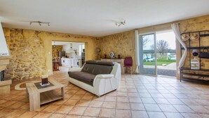 Ein großzügiger Wohnraum mit einer Couch, einem Couchtisch und Blick auf den Garten durch eine Schiebetür.