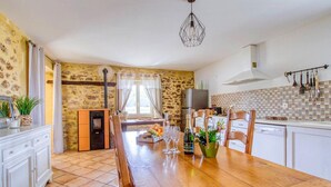 Eine Küche mit Holztisch, weißen Schränken, einer Steinwand und einer gefliesten Spritzschutzleiste.