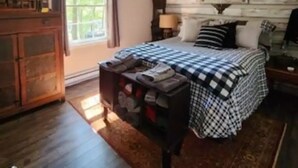 A bedroom with a bed, a ceiling fan, a dresser, a window, and a wooden wall.