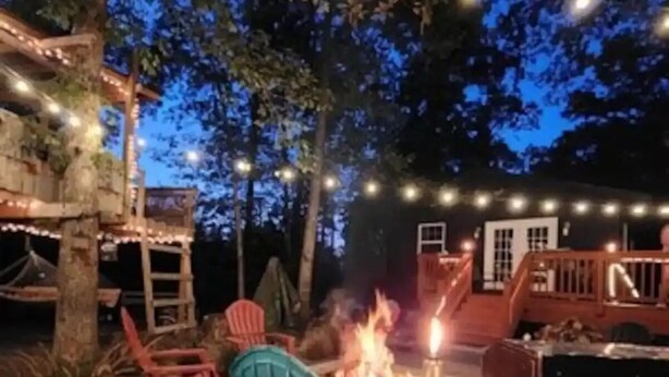 An outdoor patio area with a fire pit, string lights, and outdoor furniture.
