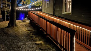 A building with a porch, a wooden fence, and string lights.