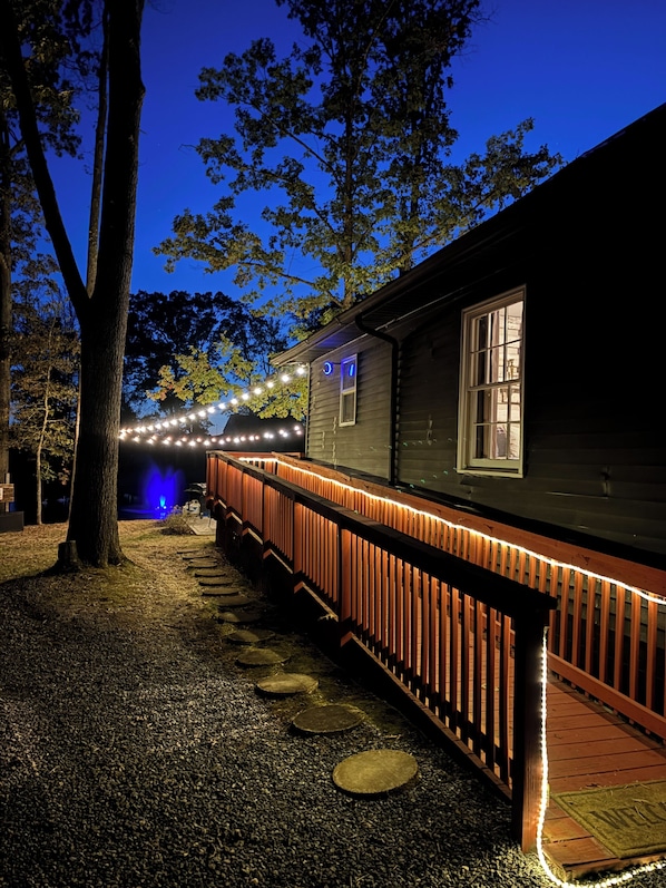 A building with a porch, a wooden fence, and string lights.