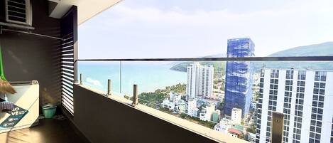 A balcony with a view of a cityscape, including tall buildings and a beach.