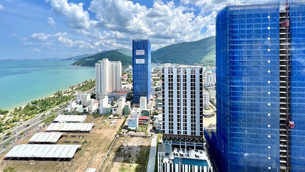 A coastal cityscape with high-rise buildings, a clear blue sky, and a view of the sea. - FLC Sea Tower -  An Phat Apartment  (Quy Nhon Nam)