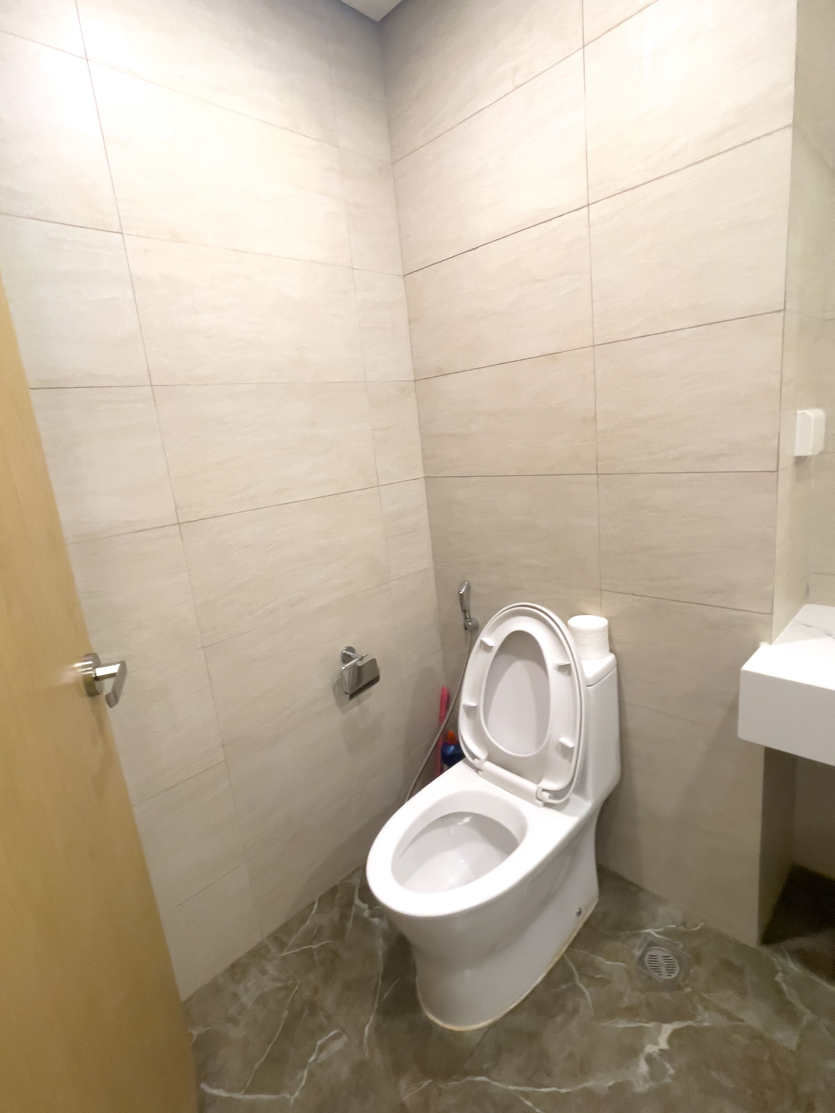 A small, tiled bathroom with a toilet, a shower, and a sink.