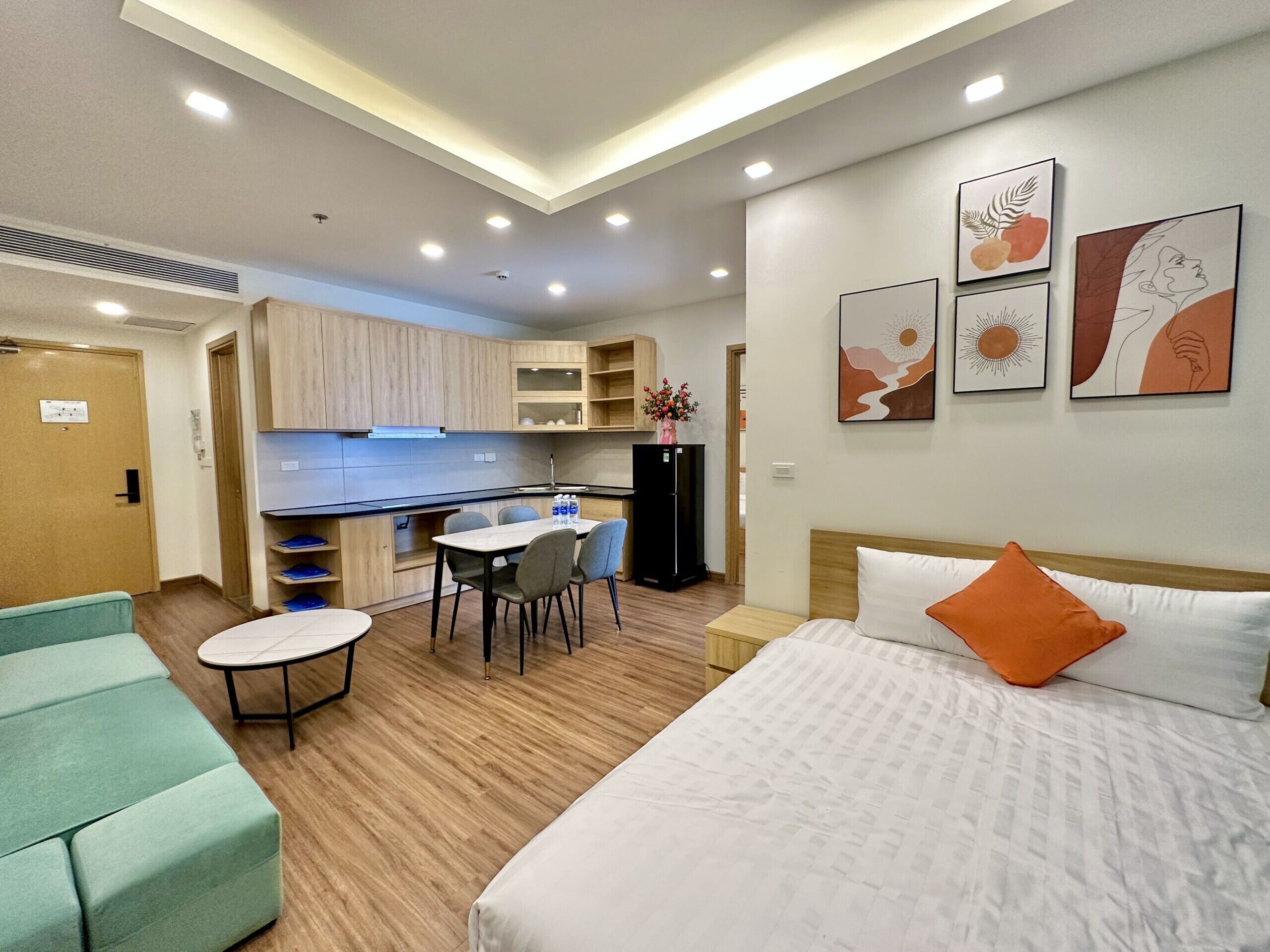 Una habitación de hotel moderna con cama, una pequeña mesa de comedor y una kitchenette.