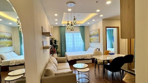 A modern hotel room with a sofa, a dining table, a small round table, and a bed. - FLC Sea Tower -  An Phat Apartment  (Quy Nhon Nam)