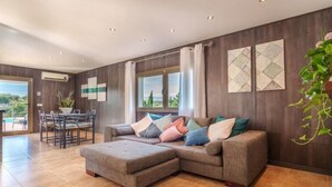 A modern living room with a sectional sofa, a dining area with a table and chairs, and a large window with curtains. - Son Alcaines Sineu by Interhome (Sineu)