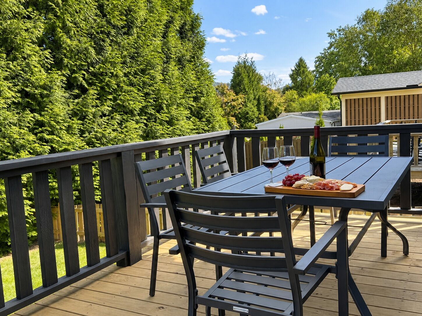 Terraza al aire libre con una mesa dispuesta para dos personas, que incluye una botella de vino, copas y una tabla con queso y uvas.