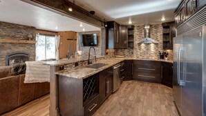A modern kitchen with dark wood cabinets, a stone backsplash, and a stainless steel refrigerator.