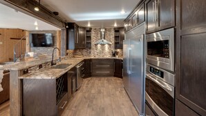 A modern kitchen with dark wood cabinets, a stone backsplash, and stainless steel appliances.