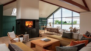Una sala de estar acogedora con chimenea, asientos cómodos y ventanas amplias que ofrecen vistas al exterior.
