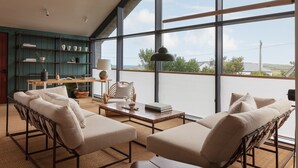 Un balcón amplio con vistas al campo, amueblado con un conjunto de sofás y una mesa de comedor.