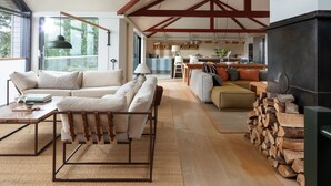 Un amplio espacio de sala con un sofá, una mesa de centro y una chimenea. Se observa una cocina al fondo, junto con un comedor.