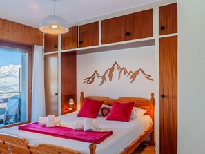 Habitación de hotel con cama, paneles de madera, un mural de montañas y vistas al exterior.
