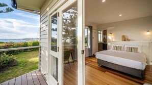 Une chambre avec un grand lit, un plancher en bois et une vue sur l’océan.
