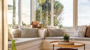 Un coin salon accueillant avec un banc rembourré, une table ronde en bois et des paniers tressés.