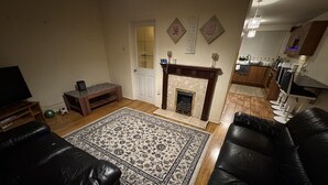 A living room with a fireplace, a television, and a dining area.