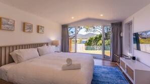 A bedroom with a large bed, a TV, and a view of the outdoors. - On the Rocks Bicheno - Bicheno Accommodation (Bicheno)