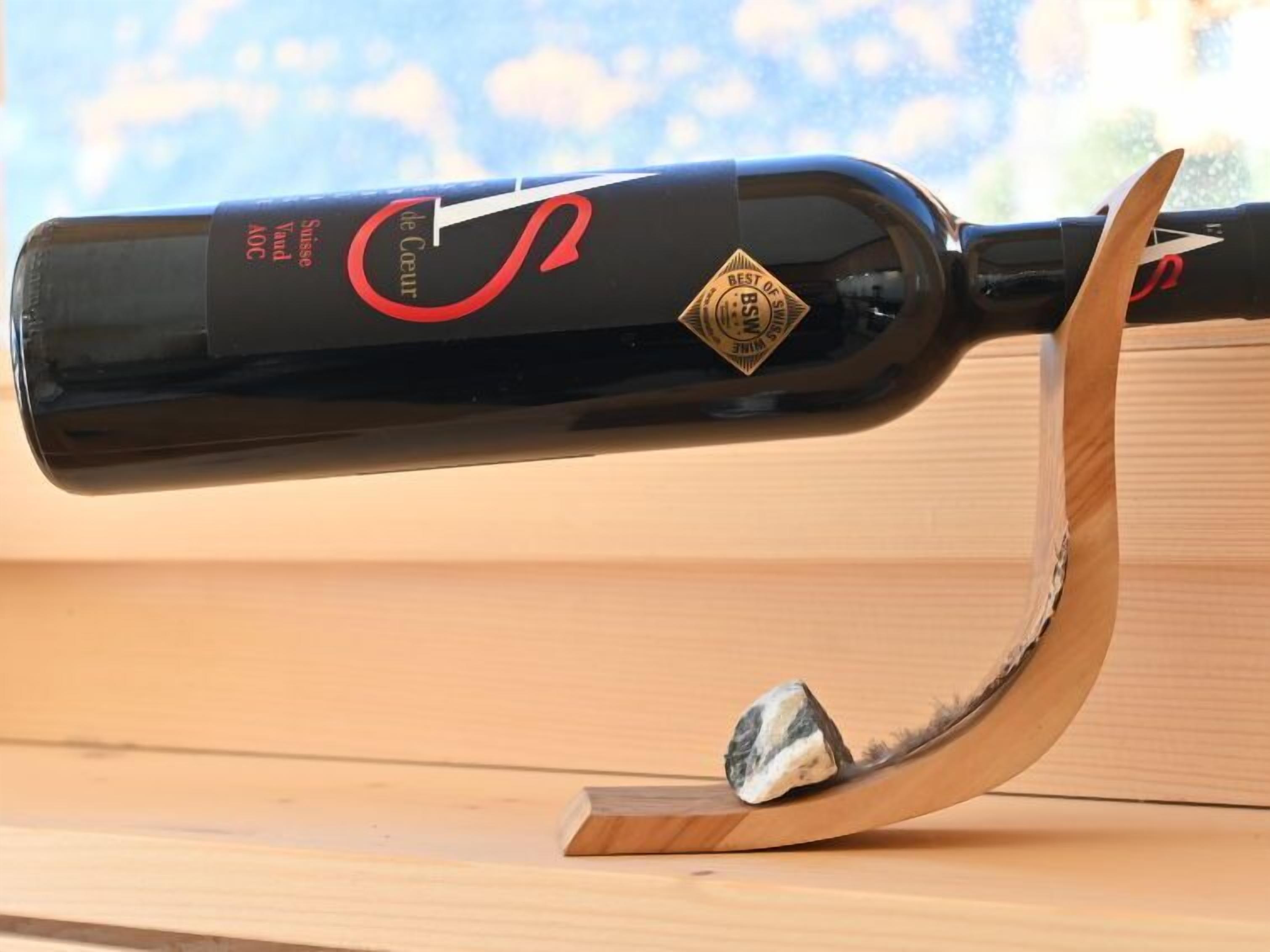 A bottle of wine on a wooden stand with a curved design.