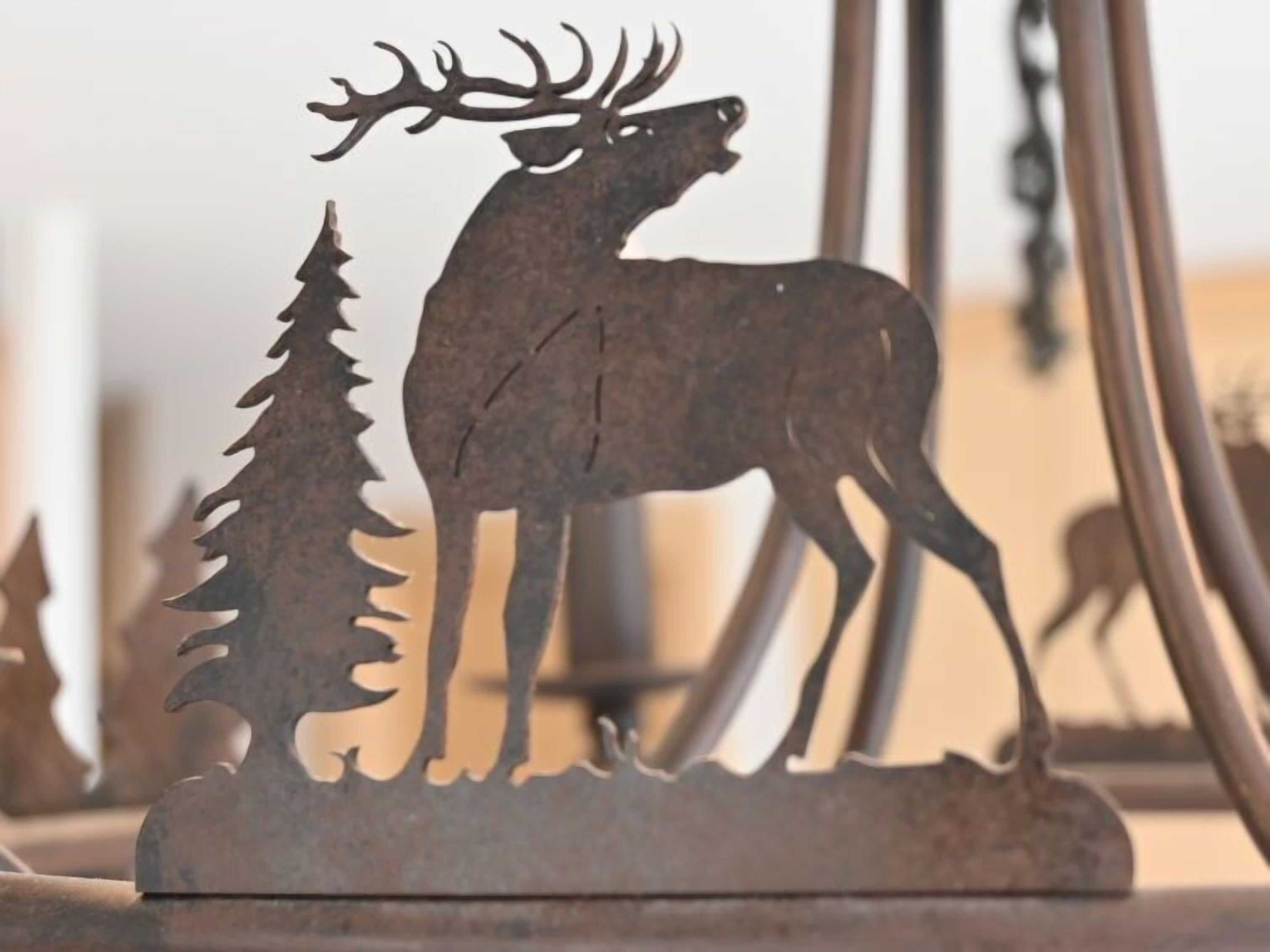 Eine Metallskulptur, die einen Hirsch mit Geweihen und einen Baum zeigt, vermutlich ein Dekorationsgegenstand.