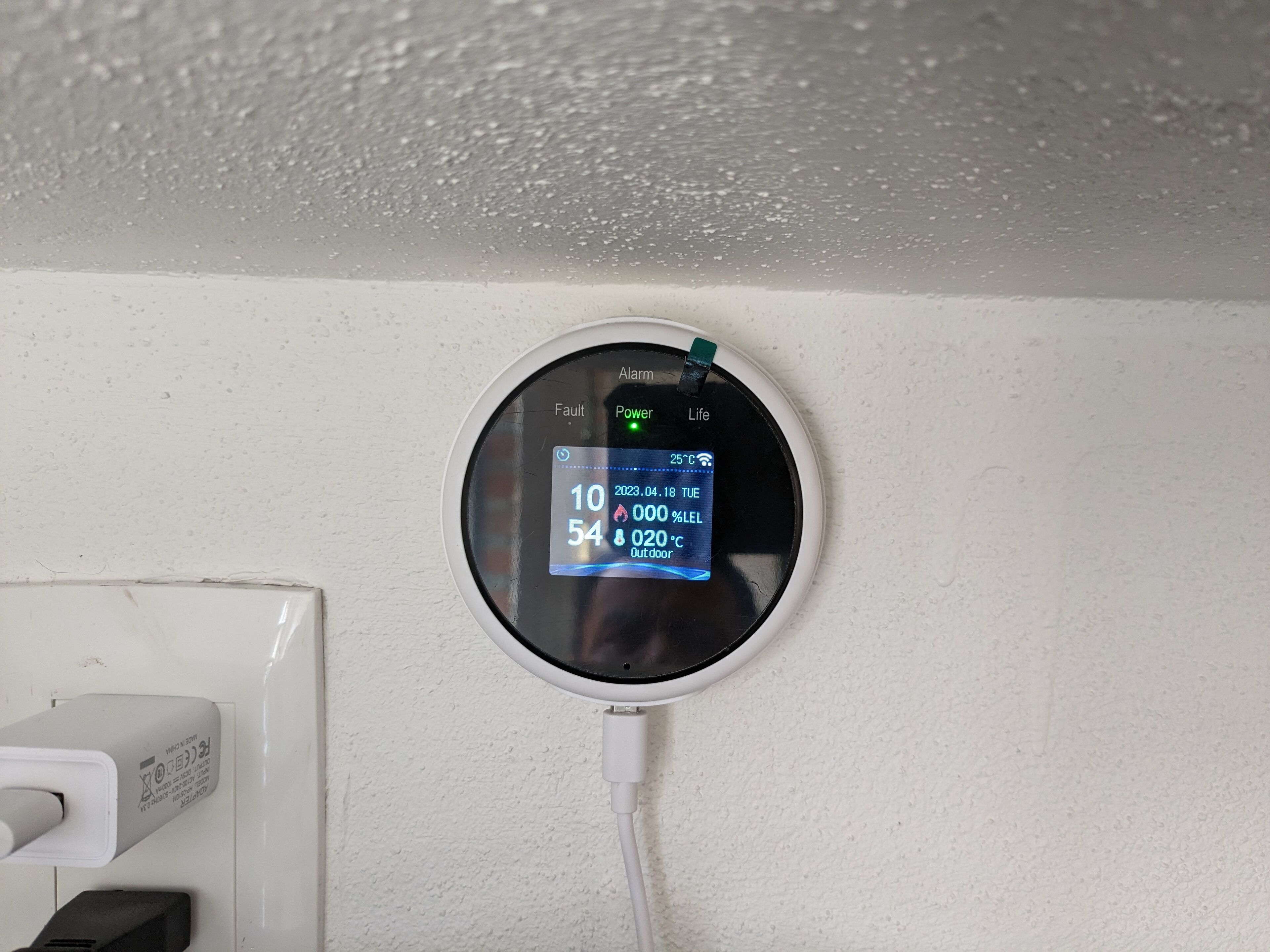 A wall-mounted thermostat displaying temperature, date, and time.