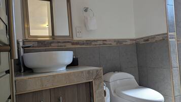 A bathroom with a white sink, a toilet, and a mirror above the sink.