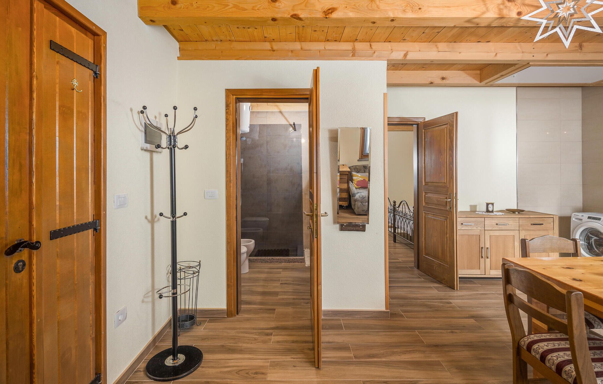 A wooden interior with a coat rack, a dining table, and a washing machine.