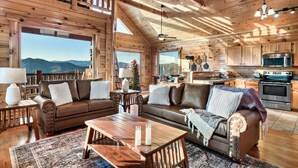 A cozy cabin interior with a living room, dining area, and kitchen. - Amazing Mtn views/Hot tub/Fireplace/Bunk beds/Arcade games (Sevierville)