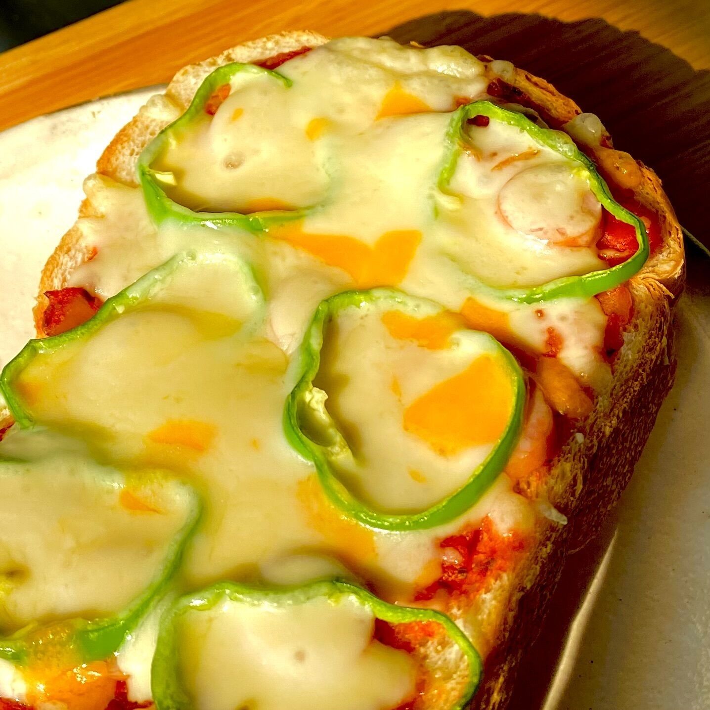Una porción de pizza con queso y tiras de pimiento verde sobre un plato blanco.
