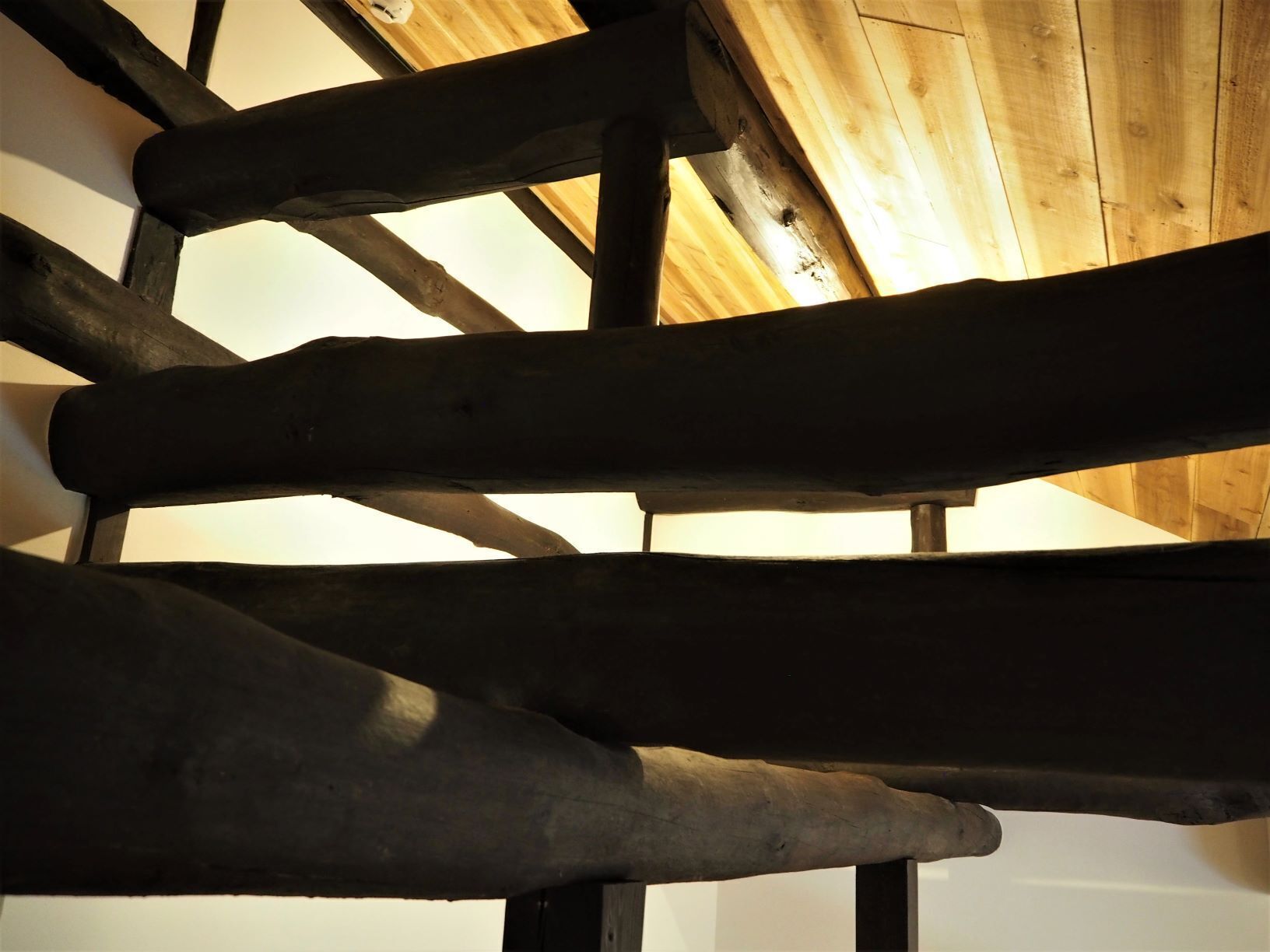 Una escalera de madera con diseño rústico, que presenta vigas a la vista y una barandilla de madera.