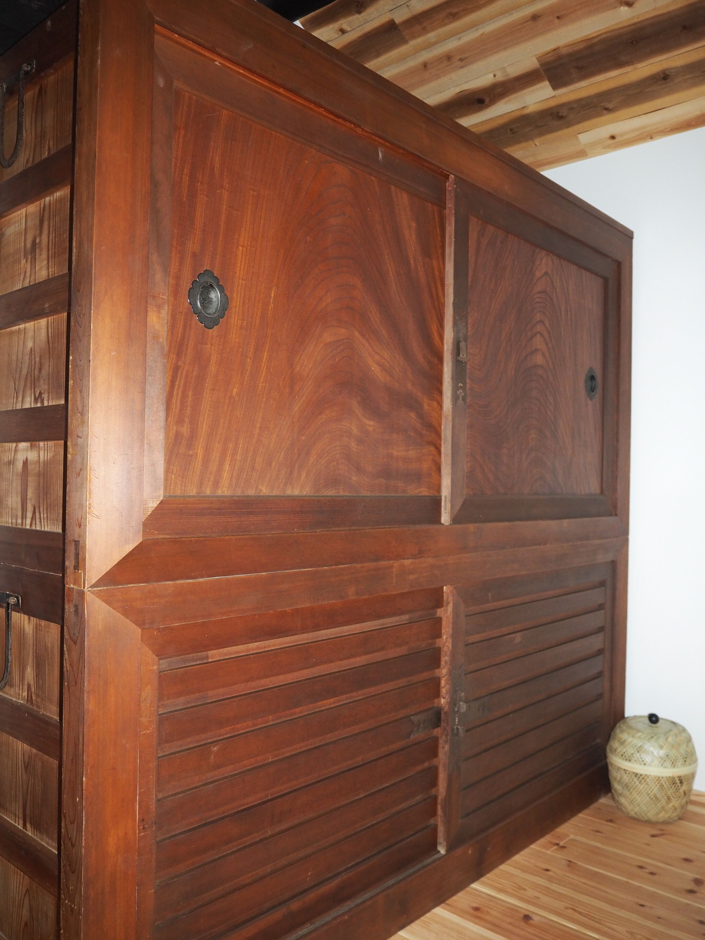 Pared de paneles de madera con un hueco y un objeto decorativo en el suelo.