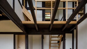 A modern interior with exposed wooden beams, a staircase, and a minimalist design. - KOTOBUKIAN (Awaji)