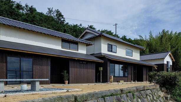 A traditional Japanese house with a tiled roof, wooden exterior, and a stone retaining wall. - KOTOBUKIAN (Awaji)