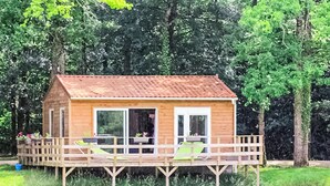 A wooden cabin with a deck, large windows, and a view of a lake. - Amazing (sta)caravan in CHEF-BOUTONNE (CHEF-BOUTONNE)