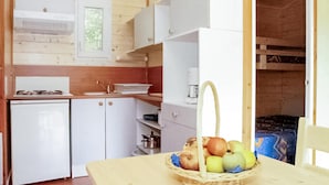 A compact kitchen with white cabinets, a sink, a stove, and a window. - Amazing (sta)caravan in CHEF-BOUTONNE (CHEF-BOUTONNE)