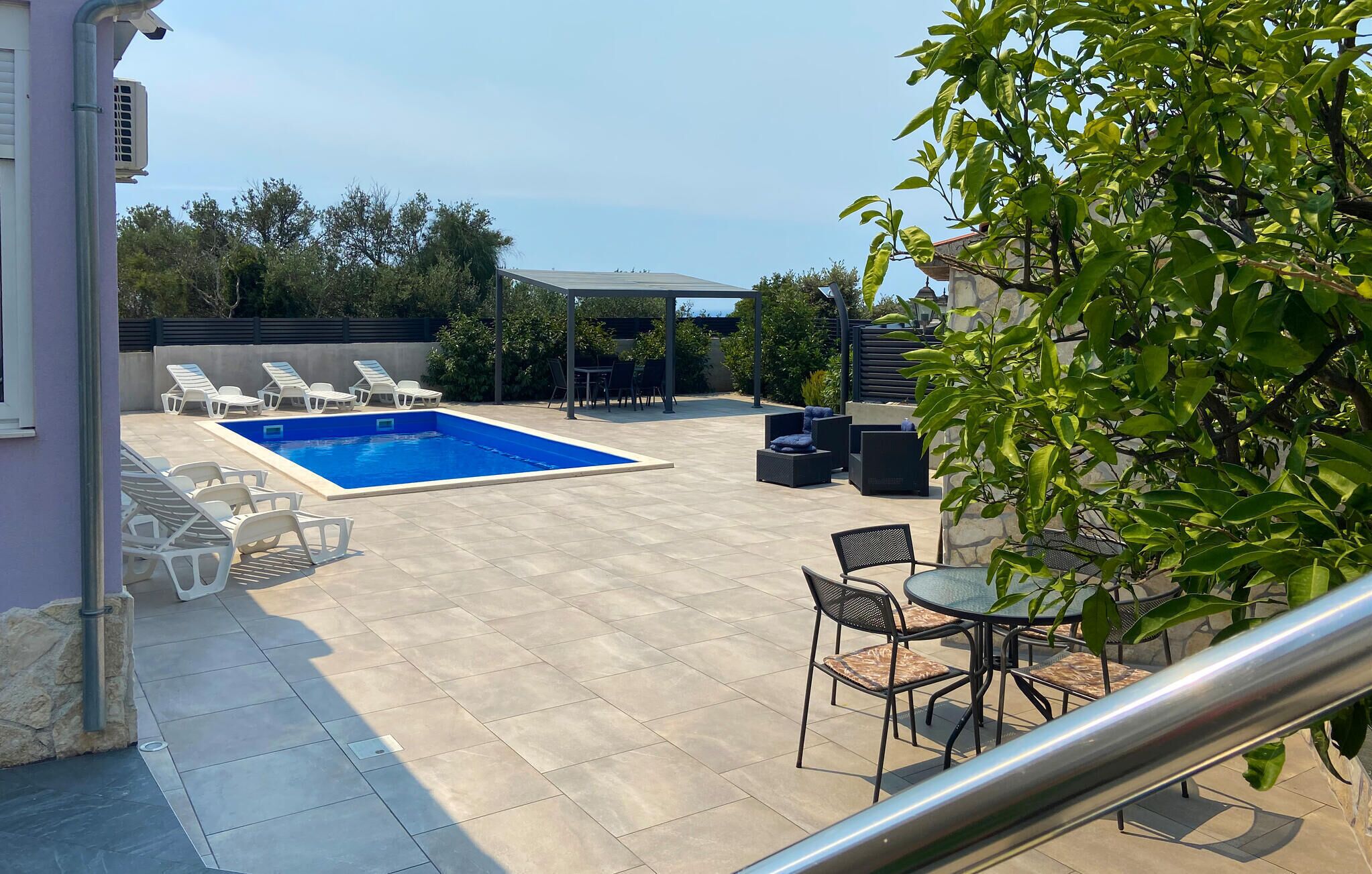 Un patio trasero con piscina, sillas de descanso y mobiliario de exterior.