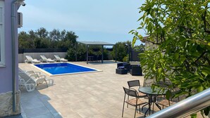 Un jardin avec une piscine, des chaises longues et du mobilier d’extérieur.