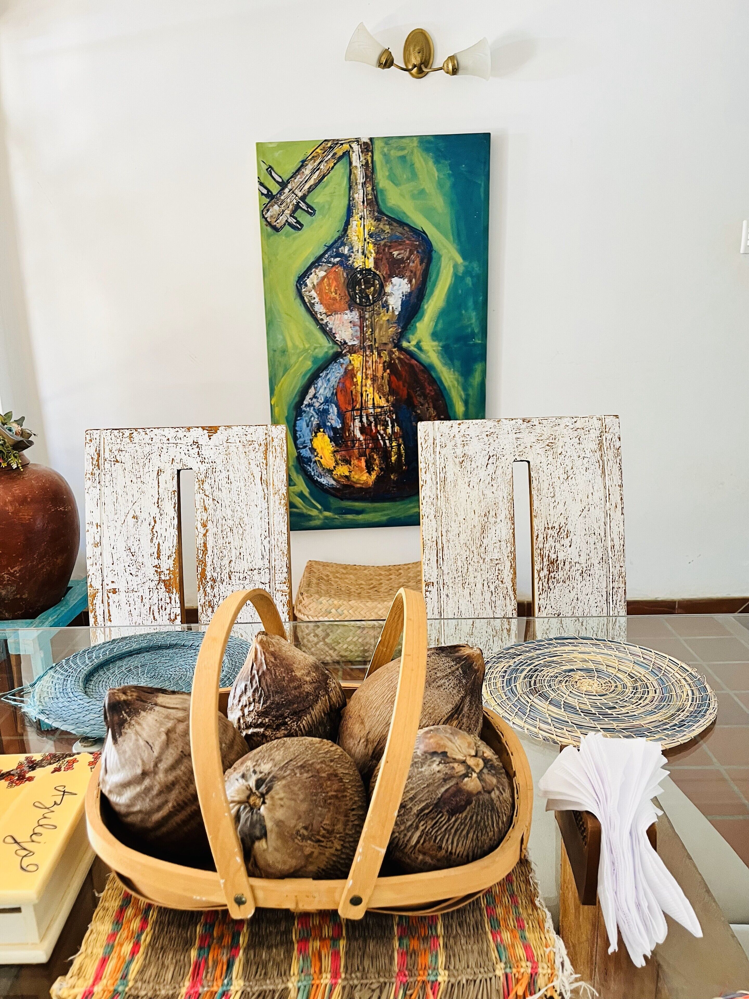 A room with a rustic wooden chair, a woven basket, and a woven placemat on the floor.