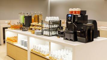 Una estación de café con varias máquinas de café, un dispensador de bebidas y una variedad de tazas y recipientes.