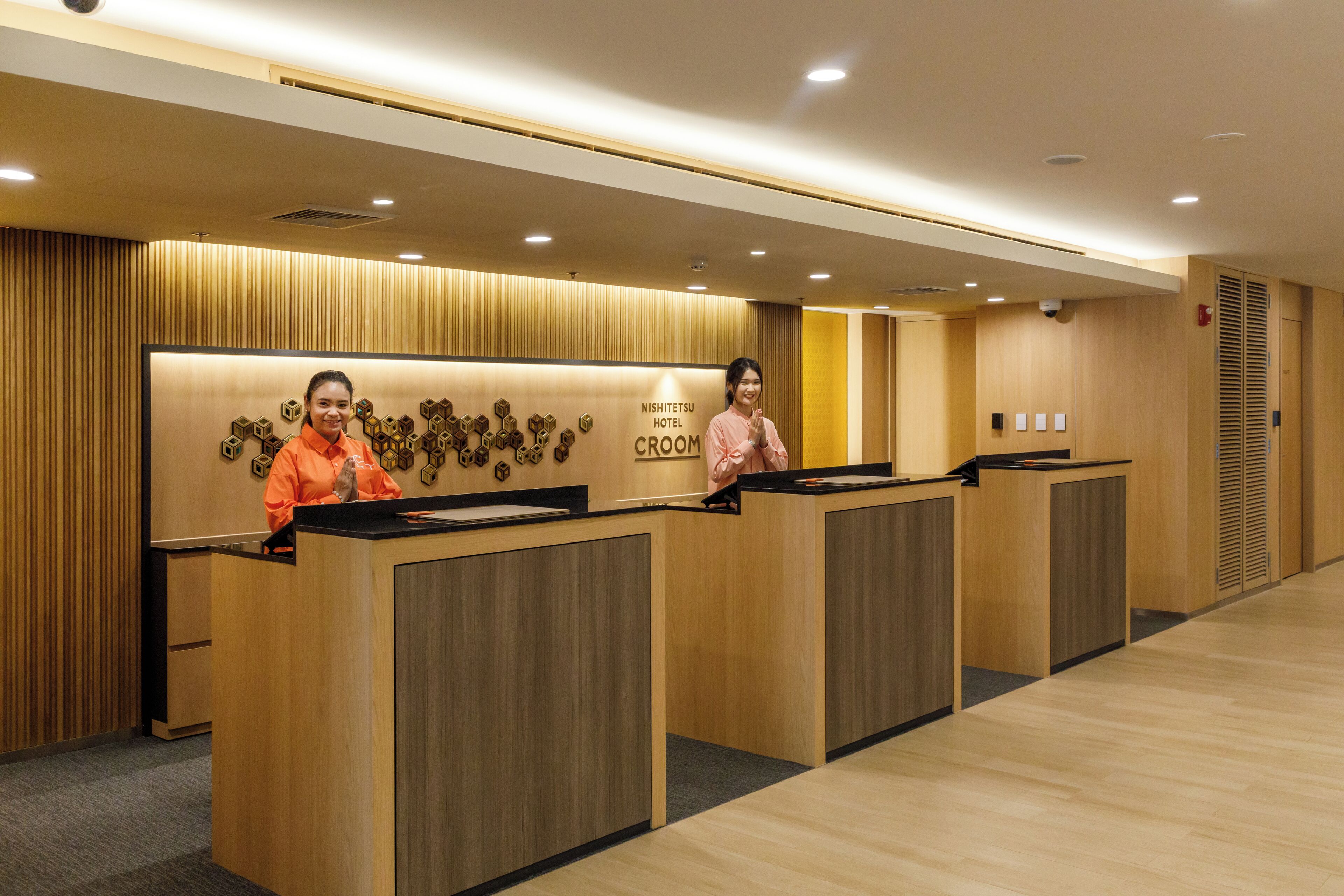 A reception area with wooden reception desks and a wall with hexagonal patterns.