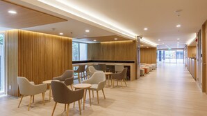 A modern hotel lobby with a long corridor, seating area with chairs and tables, and a reception desk. - Nishitetsu Hotel Croom Bangkok Silom (Bangkok)